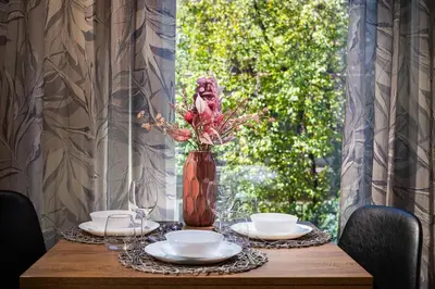 a table with plates and a vase with flowers on it at New, Modern And Convenient in Sofia