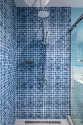 a blue tiled bathroom with a shower with a glass door at Alla Prima - 1BD Flat in Sofia Centre by Flat Mаnager in Sofia