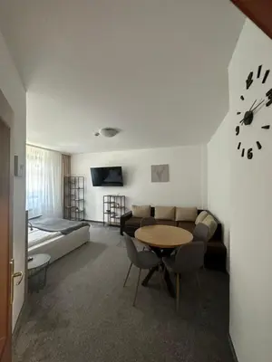 a living room with a table and a bed and a clock at Апартхотел Флора 213Б in Borovets