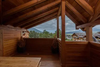 a large wooden porch with a view of a mountain at Уютен апартамент с гледка в к-с Пирин Голф in Razlog