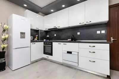 a kitchen with white cabinets and a black wall at Comfy Apartment with Private Parking in Plovdiv