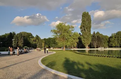 a park with a pond and people walking around at Apartment South Park - Louis Eyer in Sofia