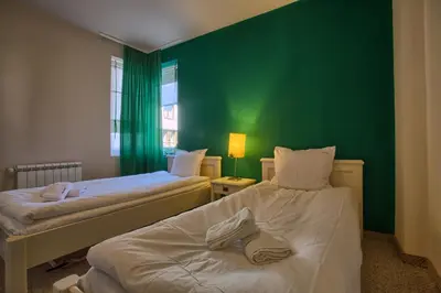 two beds in a room with a green wall at Bansko Royal Towers - 2BD Flat with Parking by Flat Mаnager in Bansko