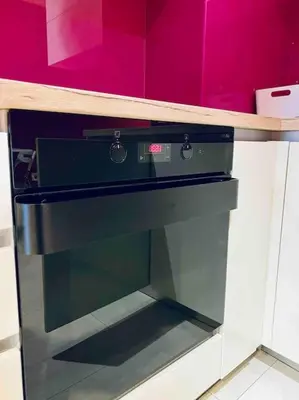 a black oven in a kitchen with a pink wall at Magenta Apartment with free WiFi in Sofia