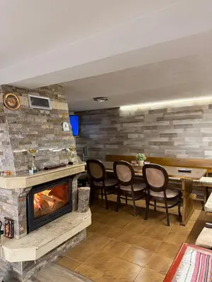 a living room with a fireplace and a table and chairs at Вила за гости “Попина лъка” in Vikhren