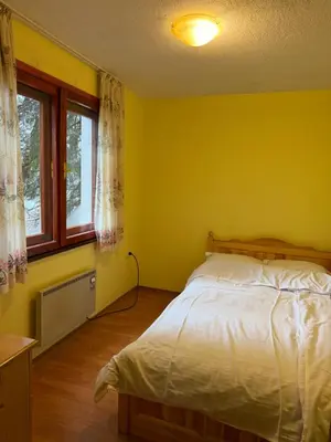 a yellow bedroom with a bed and a window at Вила за гости “Попина лъка” in Vikhren