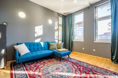 a living room with a blue couch and a rug at Stylish Stay - 2BDR, 2BTHR+ Free Parking in Sofia