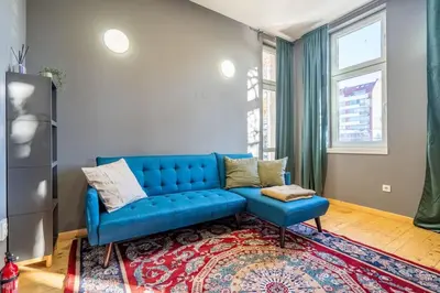 a living room with a blue couch and a rug at Stylish Stay - 2BDR, 2BTHR+ Free Parking in Sofia