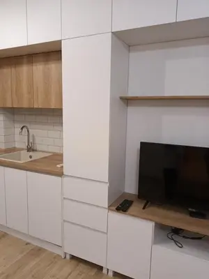 a kitchen with white cabinets and a flat screen tv at Студио Ели - Пловдив in Plovdiv