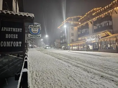 a snow covered street in front of a building at Private Suite at Comfort Bansko in Bansko
