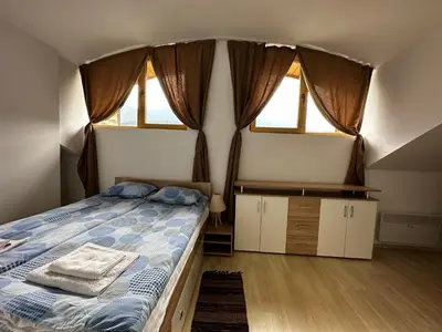 a bedroom with a bed and two windows at Cozy duplex apartment in St. John Park in Bansko