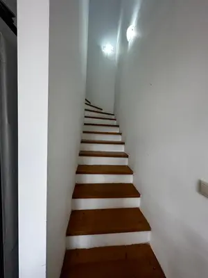 a stairway with white walls and wooden stairs at Cozy duplex apartment in St. John Park in Bansko