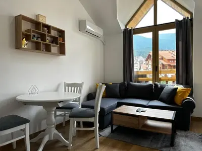a living room with a couch and a table and a window at Cozy duplex apartment in St. John Park in Bansko