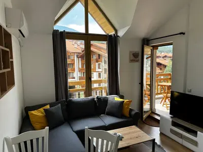 a living room with a couch and a large window at Cozy duplex apartment in St. John Park in Bansko
