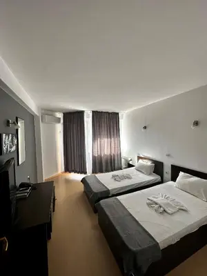 a hotel room with two beds and a television at Хотел Костенец in Kostenets Village