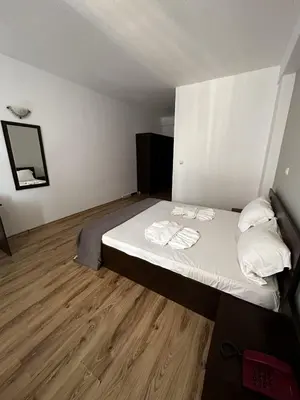 a bedroom with a bed with white sheets and towels at Хотел Костенец in Kostenets Village