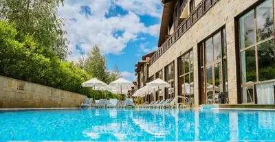 a swimming pool with chairs and umbrellas next to a building at Apartament by Zenit in Terra Complex B30 in Razlog
