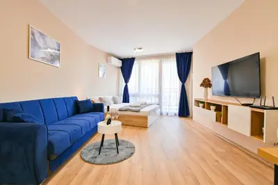 a living room with a blue couch and a tv at Armand de Azurro in Sofia