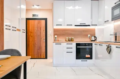 a kitchen with white cabinets and a wooden door at Armand de Azurro in Sofia