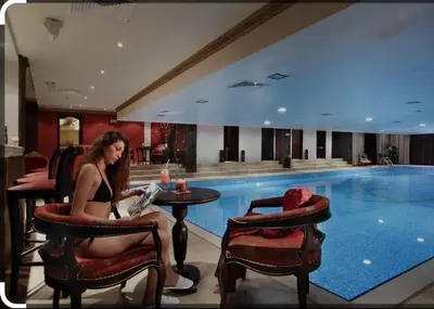 a woman sitting in a chair next to a swimming pool at Snow Mountain Grand Monastery in Pamporovo