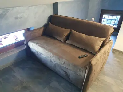 a brown couch in a room with a window at Snow Mountain Grand Monastery in Pamporovo