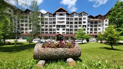 a large building with a flower pot in the grass at Borovets Dream Studio in Borovets