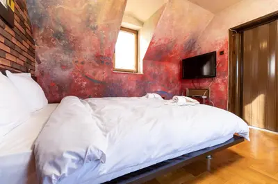 a bedroom with a white bed with a red wall at Penthouse Tepeto in Plovdiv