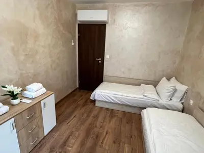 a small room with two beds and a wooden floor at Апартамент Комфорт 2 Близо до Летището in Sofia