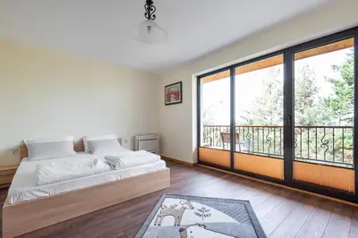 a bedroom with a bed and a balcony at ВИЛА МАРИНОВИ in Boykovo