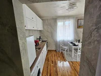 a kitchen with white cabinets and a table in it at Апартамент за гости Боляри in Velingrad