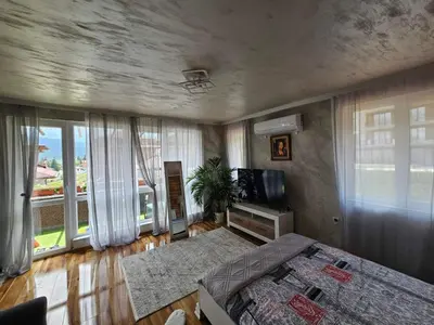 a bedroom with a bed and a tv and windows at Апартамент за гости Боляри in Velingrad