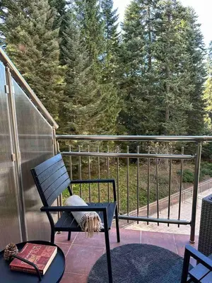 a rocking chair on a balcony with trees in the background at Sana Ski apartment 313A in Flora, Borovets in Borovets