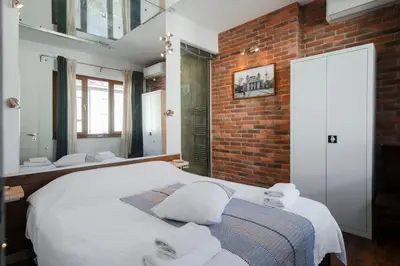 a bedroom with a white bed and a brick wall at Designer 1BD Cinématique on Solunska by Flat Mаnager in Sofia