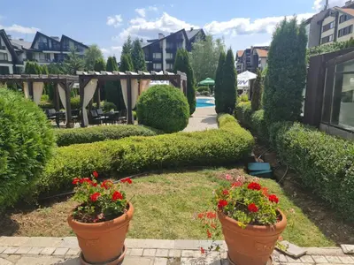 a garden with two large pots of red flowers at Aspen Golf D 401 in Bansko