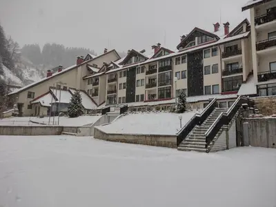 a snow covered parking lot in front of a building at Antonovi Apartments Deluxe in hotel Laplandia in Pamporovo