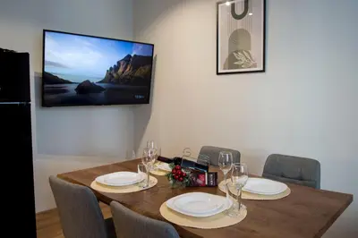 a dining room table with chairs and a tv on the wall at Antonovi Apartments Deluxe in hotel Laplandia in Pamporovo