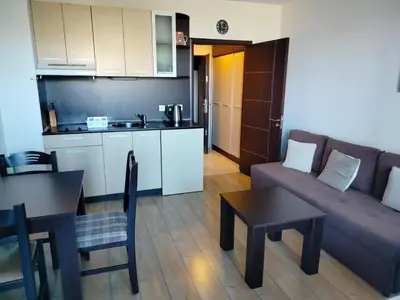 a living room with a couch and a table and a kitchen at Alpine Lodge Bansko Apartments in Bansko