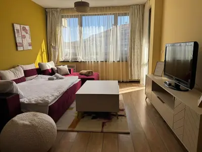 a living room with a bed and a flat screen tv at Alpine Lodge Bansko Apartments in Bansko
