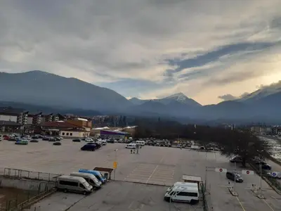 a parking lot with parked cars and mountains in the background at Gondola lift apartment 5402 in Bansko