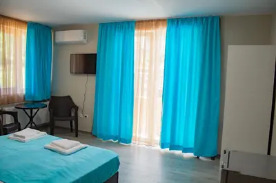 a room with blue curtains and a bed and a table at Guesthouse The Rock in Sapareva Banya