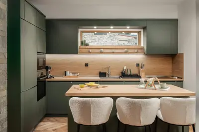 a kitchen with green cabinets and a kitchen island with chairs at Luxury Villa with Hot Pool in Banya