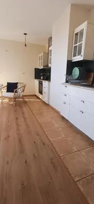 a kitchen with white cabinets and a wooden floor at апартамент Римската стена in Hisarya