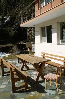 a wooden picnic table and two benches in front of a building at Къща за гости Донука in Panichishte