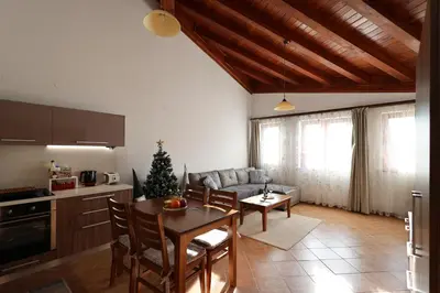 a kitchen and living room with a table and a couch at Pirin Golf Mountain View Retreat in Razlog
