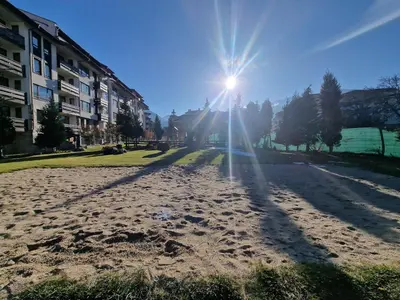a sun is shining on a dirt road at Bansko Royal Towers George Apartment, next to the Gongola in Bansko