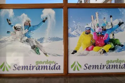 a sign with four people sitting in the snow at BH & Semiramida Ski Apartment in Borovets
