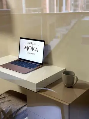 a laptop computer sitting on a white table with a cup at Мoka Apartment in Sofia