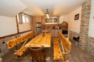 a dining room with a wooden table and benches at Къща за гости Оскови in Velingrad