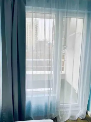 a window with a white curtain in a room at Modern Turquoise Apartment/free WiFi in Sofia