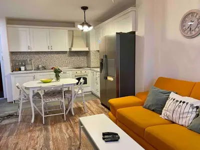 a living room with a couch and a table and a kitchen at Stylish Magenta Apartment - terrace & free parking in Sofia